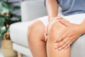 Persoon met beide handen op pijnlijke knie, mogelijk in afwachting van een knieoperatie bij Máxima Nova