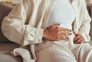 Persoon houdt hand op onderbuik, mogelijk vanwege klachten die wijzen op een liesbreuk