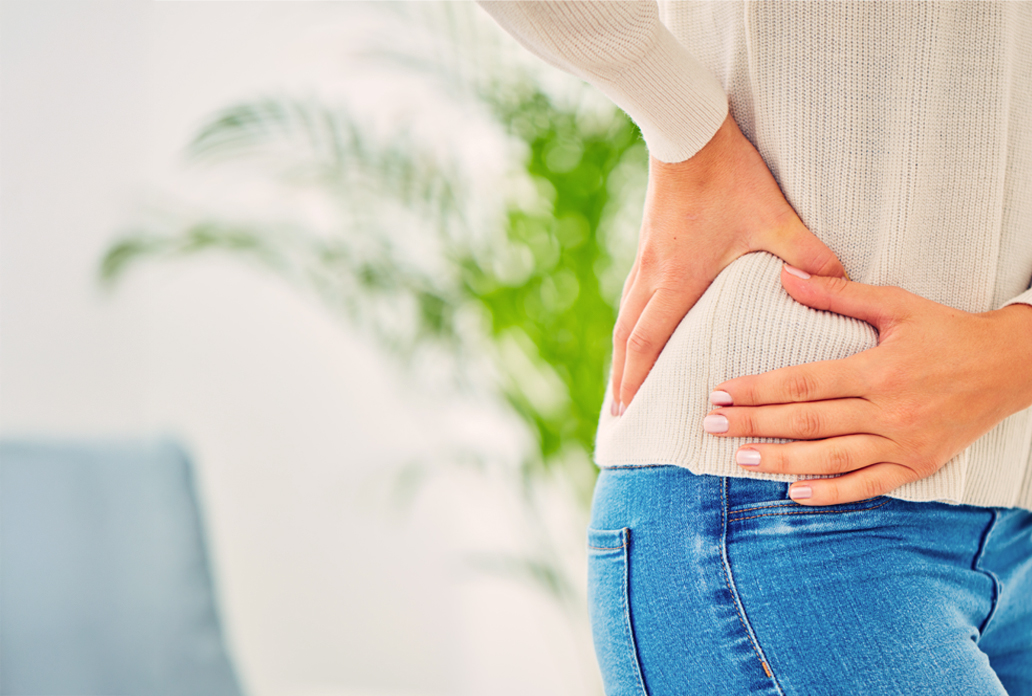 Persoon met hand op pijnlijke heup, mogelijk in afwachting van heupbehandeling bij Máxima Nova