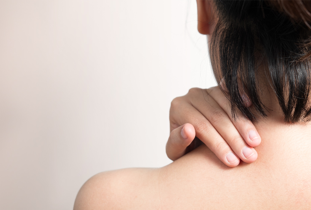 Persoon raakt met hand de schouder aan bij mogelijk verdacht huidplekje