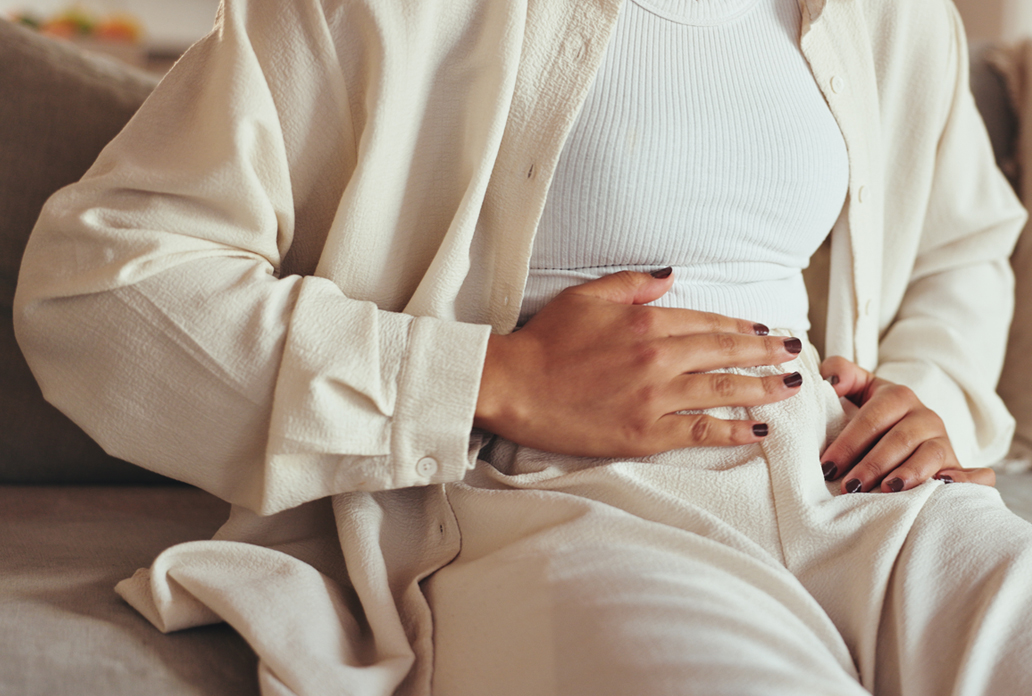 Persoon houdt hand op onderbuik, mogelijk vanwege klachten die wijzen op een liesbreuk